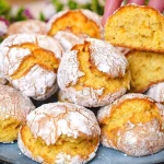 Galletas de naranja recién horneadas y esponjosas sobre una superficie de madera.